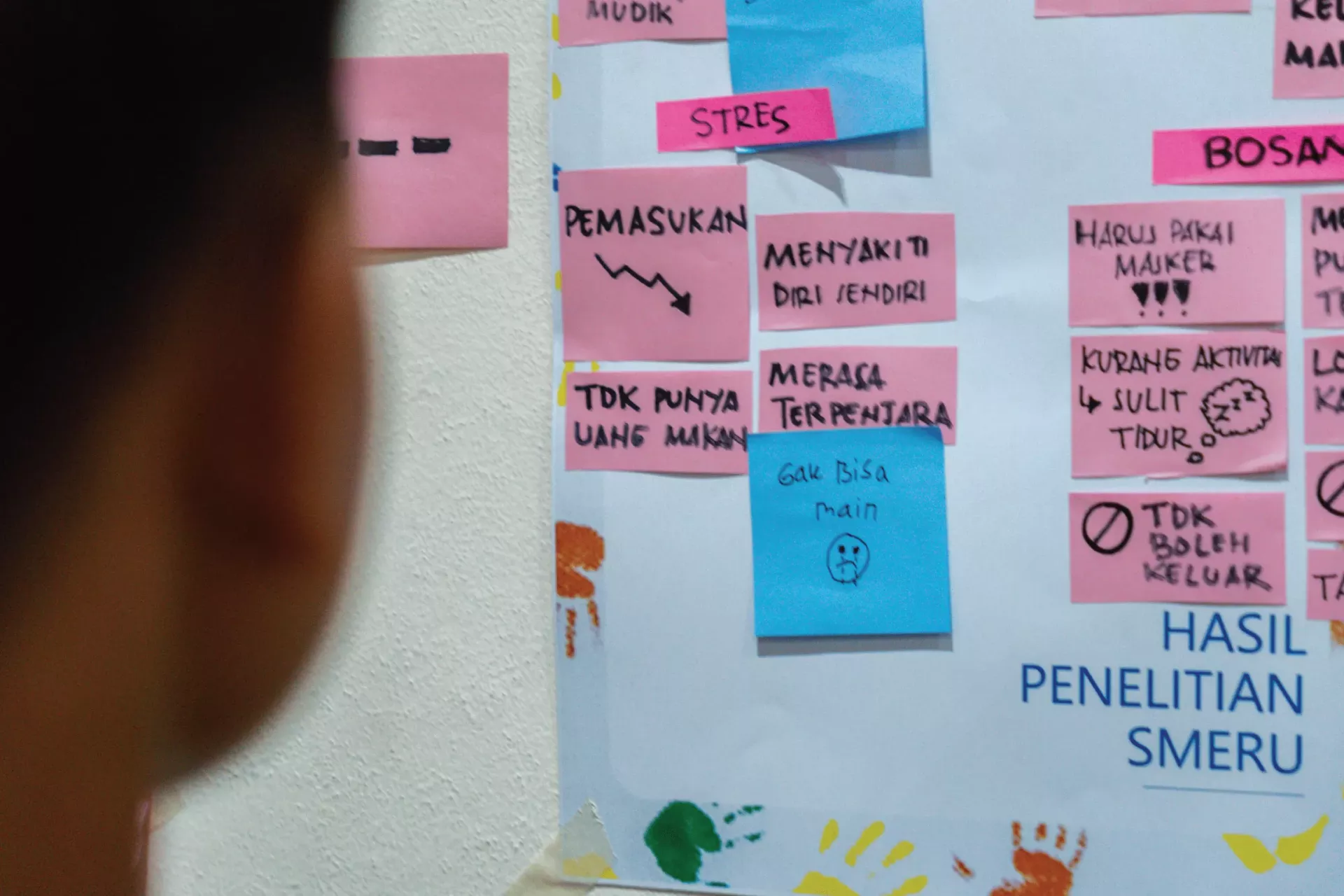 An adolescent looking at post-it notes during a workshop