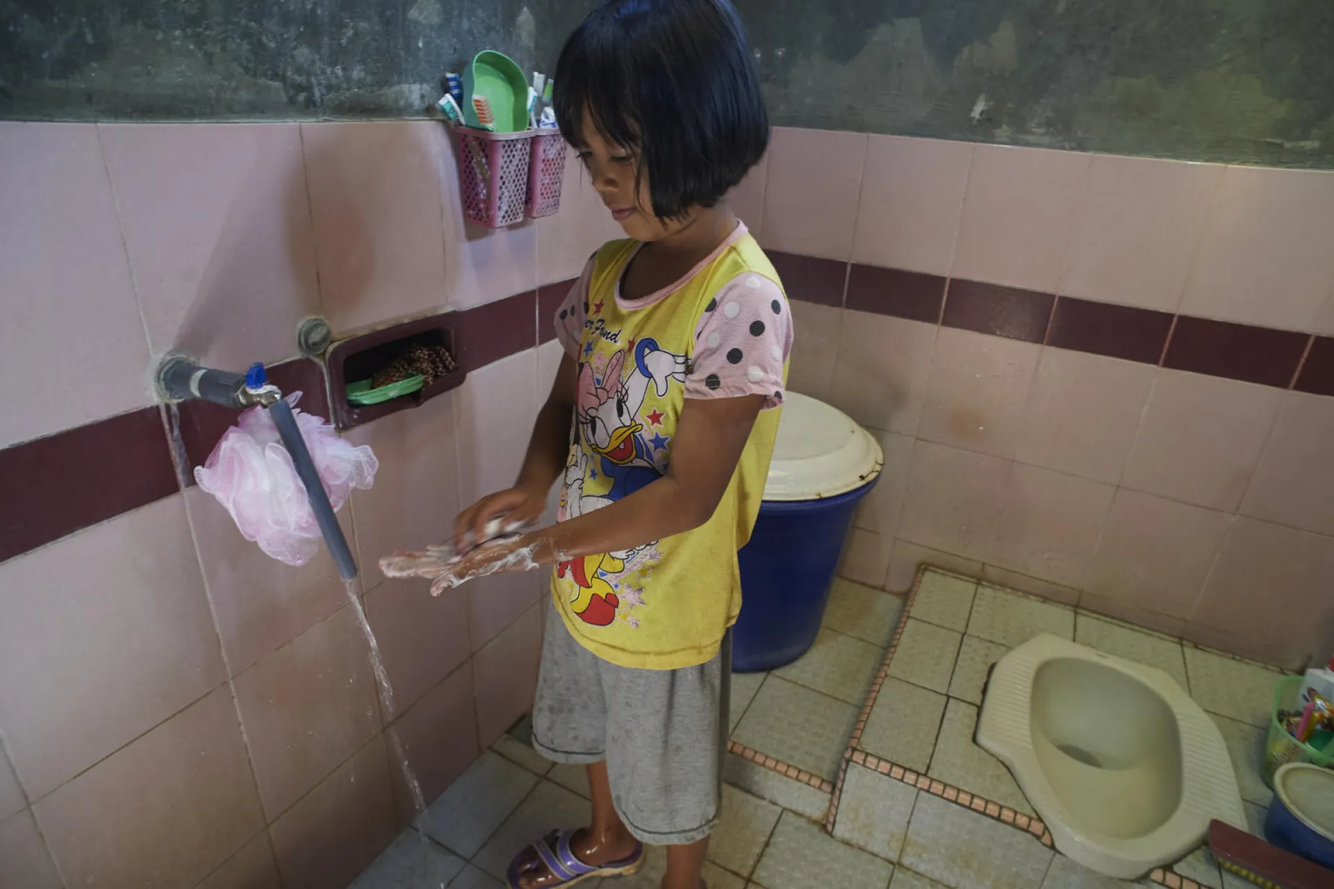 A girl washes her hands with soap