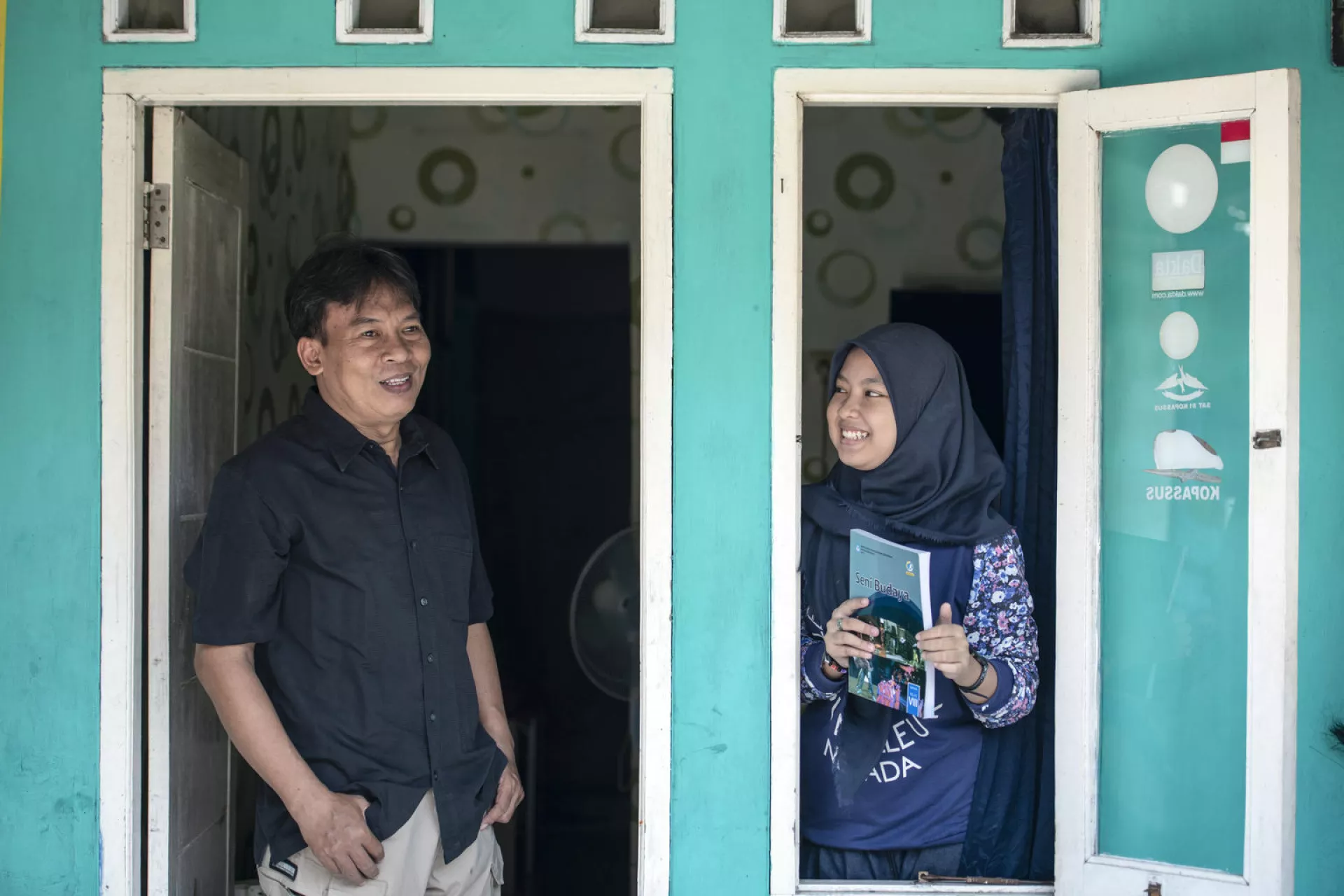 A father and a daughter standing in front of their house 