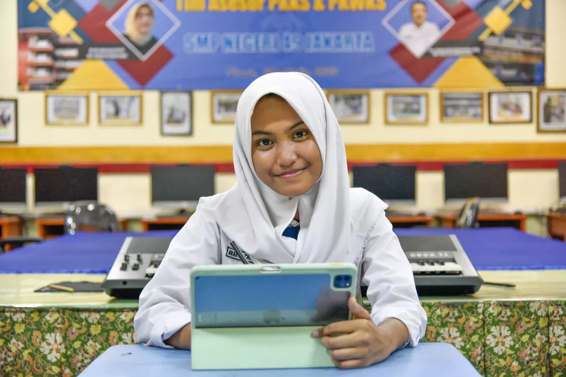 A girl smiling using her tablet in her classroom