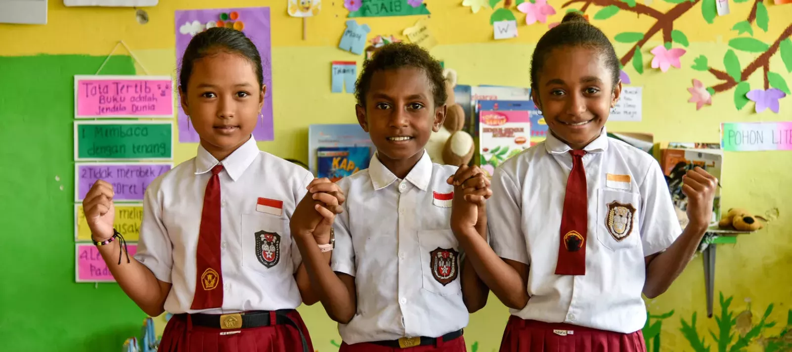 Three primary school students smile