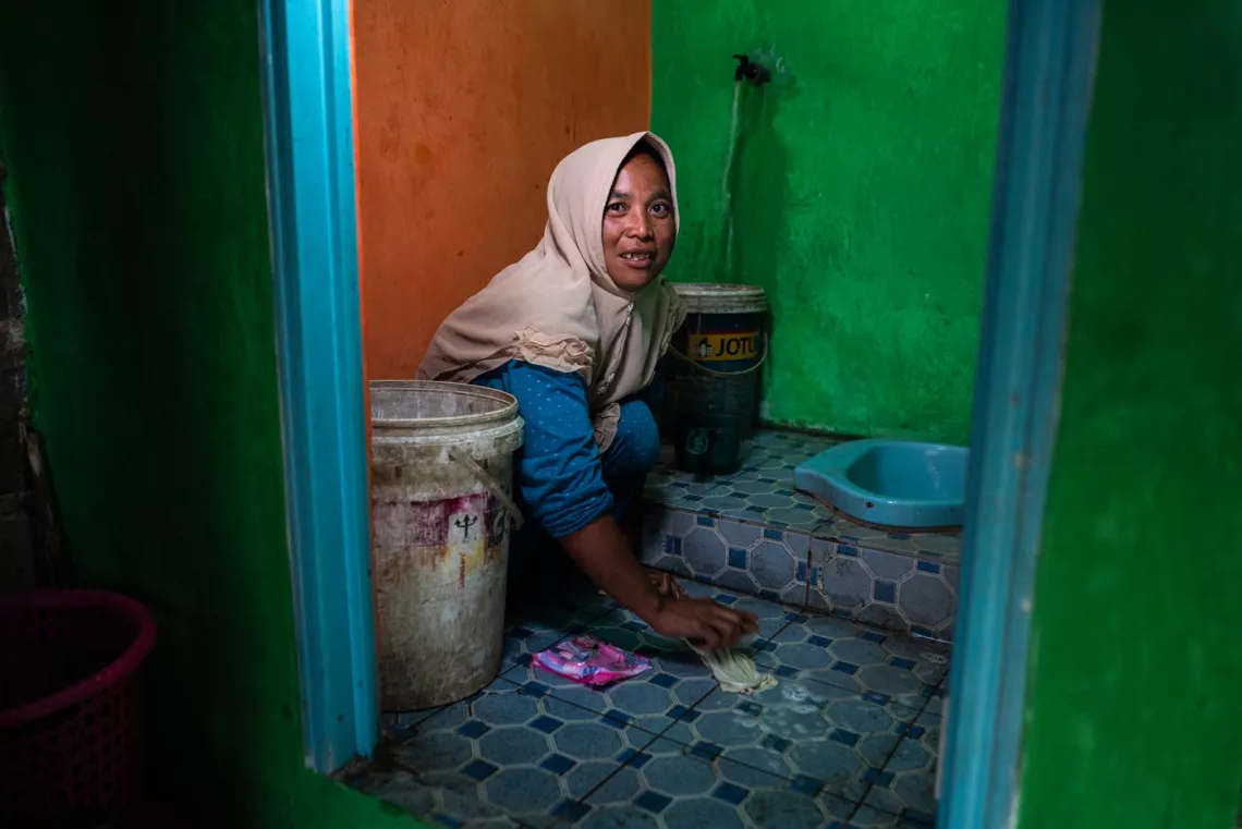 Wahyu washes her son's clothes in a newly constructed sanitation facility in her home
