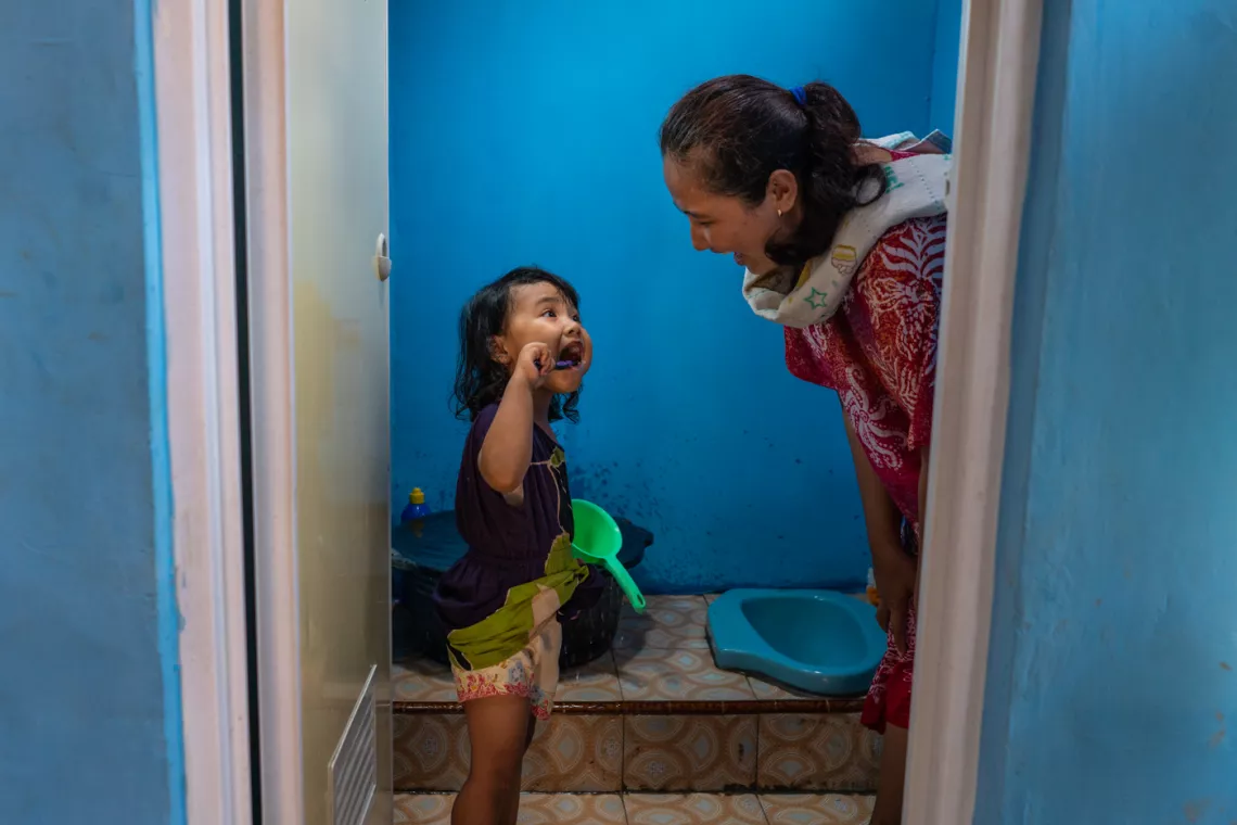 Fika, 3, brushes her teeth with her mother Rini Ratikasari in a newly constructed toilet in their home