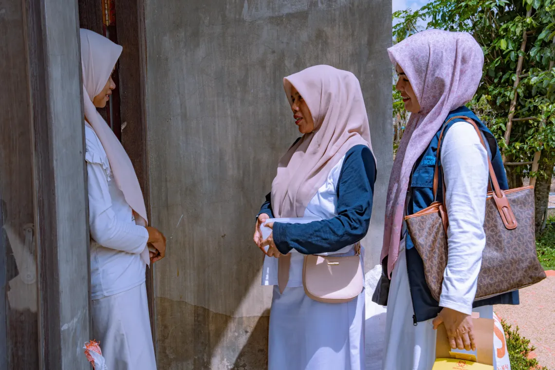 From right to left: Marlina, immunization coordinator and vaccinator at Padang Tiji Community Health Centre (Puskesmas), and her colleague, visit Dahniar&rsquo;s home to talk to her about the benefits of vaccinating her nine-month-old son. Pidie District, Aceh Province, Indonesia.