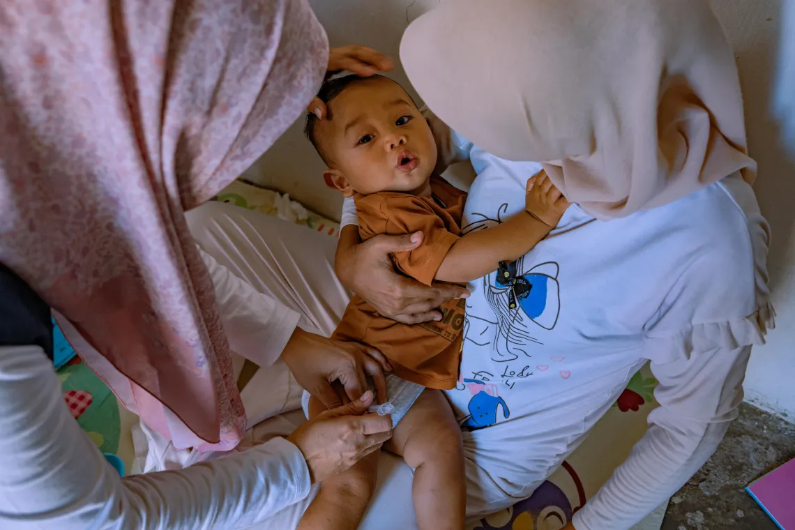 Marlina (left), immunization coordinator and vaccinator at Padang Tiji Community Health Centre (Puskesmas), and her colleague, vaccinate nine-month-old Shaquel, Pidie District, Aceh Province, Indonesia.