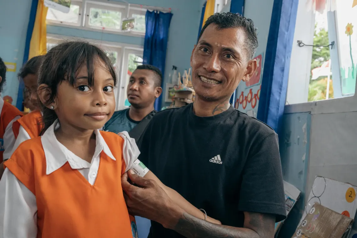 A father tries to put on a MUAC (Mid-upper arm circumference (MUAC) measuring tape at the TKN Kelapa Lima Public Early Childhood Education (ECE) Centre, Kupang Municipality, East Nusa Tenggara, on 9 December 2025