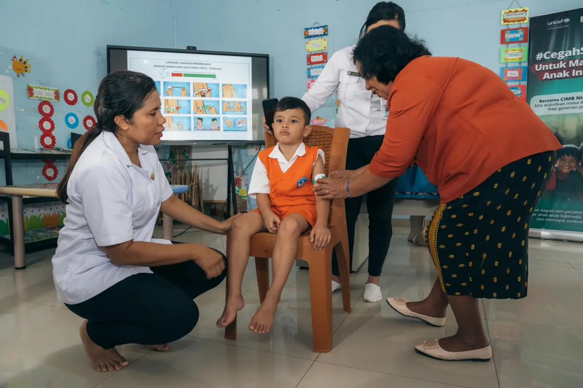 Ibu Erni Hailitik, Headmaster of TKN Kelapa Lima, tries to examine a student for signs of wasting, at the TKN Kelapa Lima Public Early Childhood Education (ECE) Centre, Kupang Municipality, East Nusa Tenggara, on 9 December 2025 
