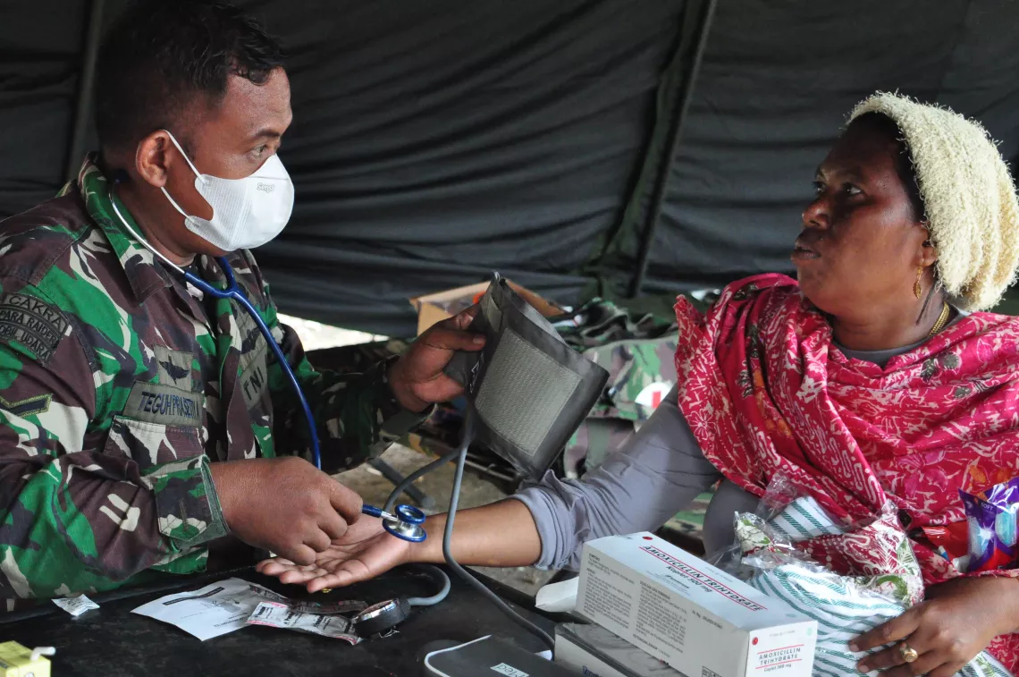 On 17 January 2020, a member of the Indonesian army examines an earthquake survivor in a shelter at Manakarra Stadium in Mamuju Regency, West Sulawesi, Indonesia.