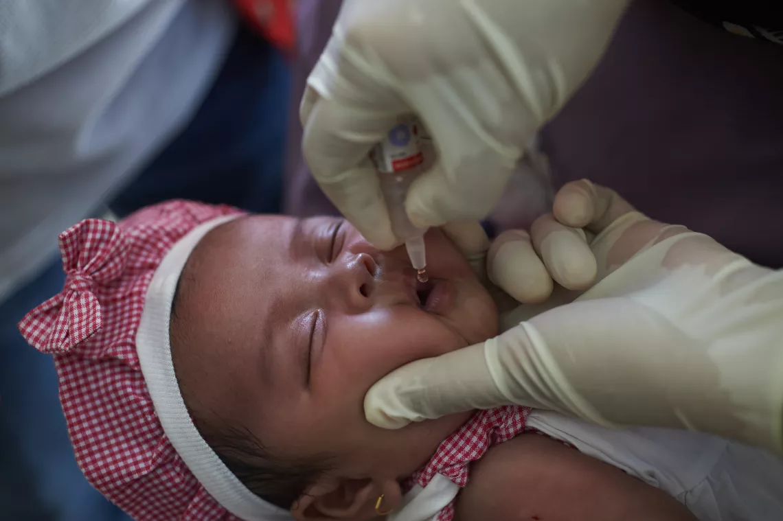 A health worker immunizes an infant with polio vaccination