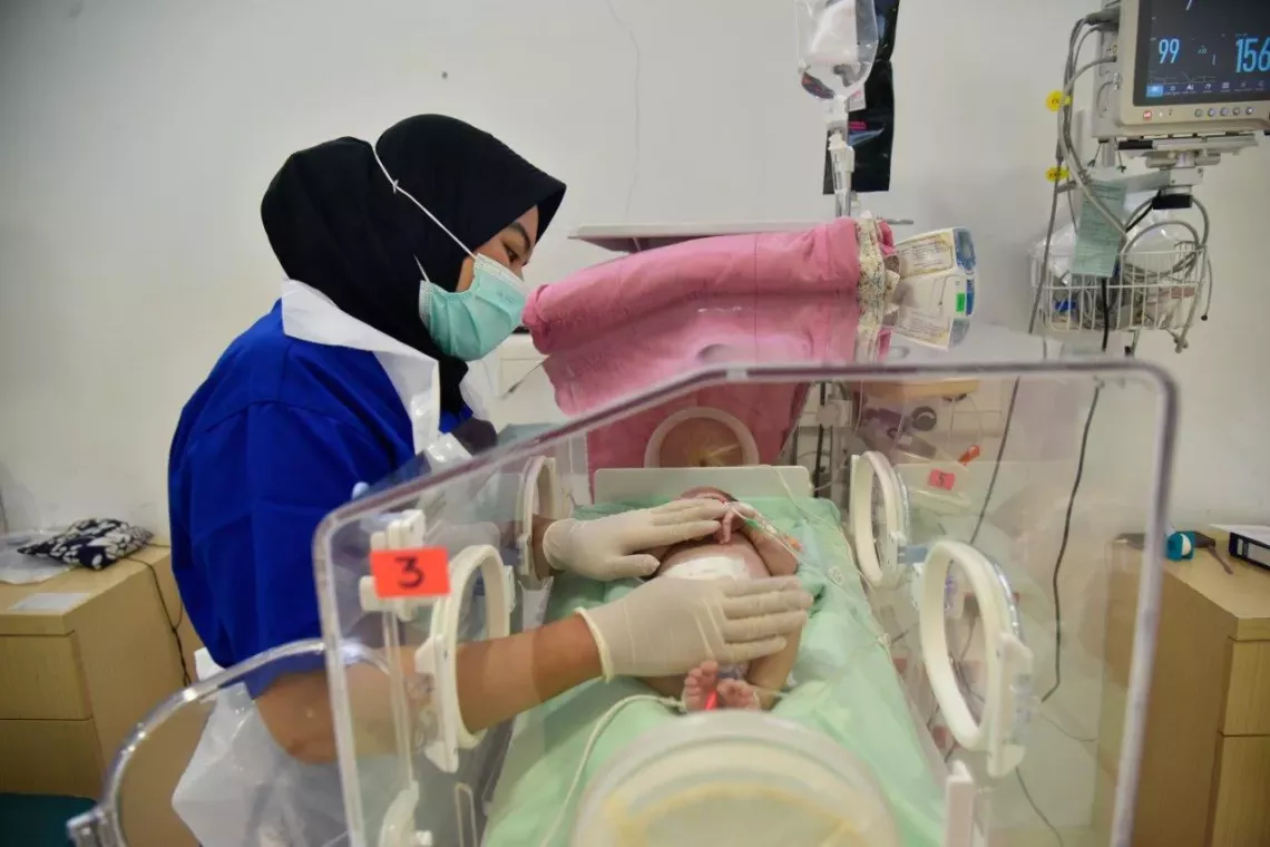 A healthworker with a baby in NICU