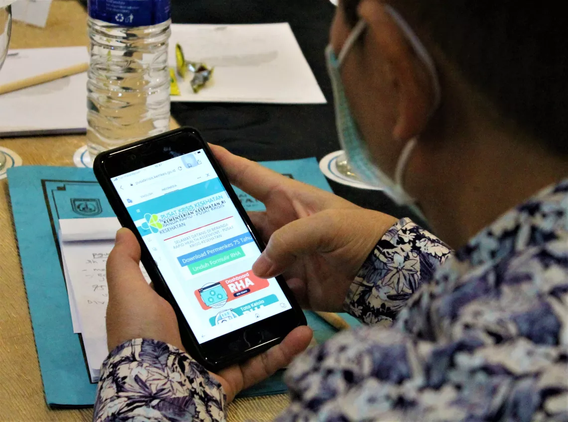 Seorang petugas dinas kesehatan belajar menggunakan aplikasi kajian cepat  kesehatan yang baru melalui ponselnya dalam sebuah lokakarya di Bogor, Jawa Barat, pada 11 Agustus 2022. 