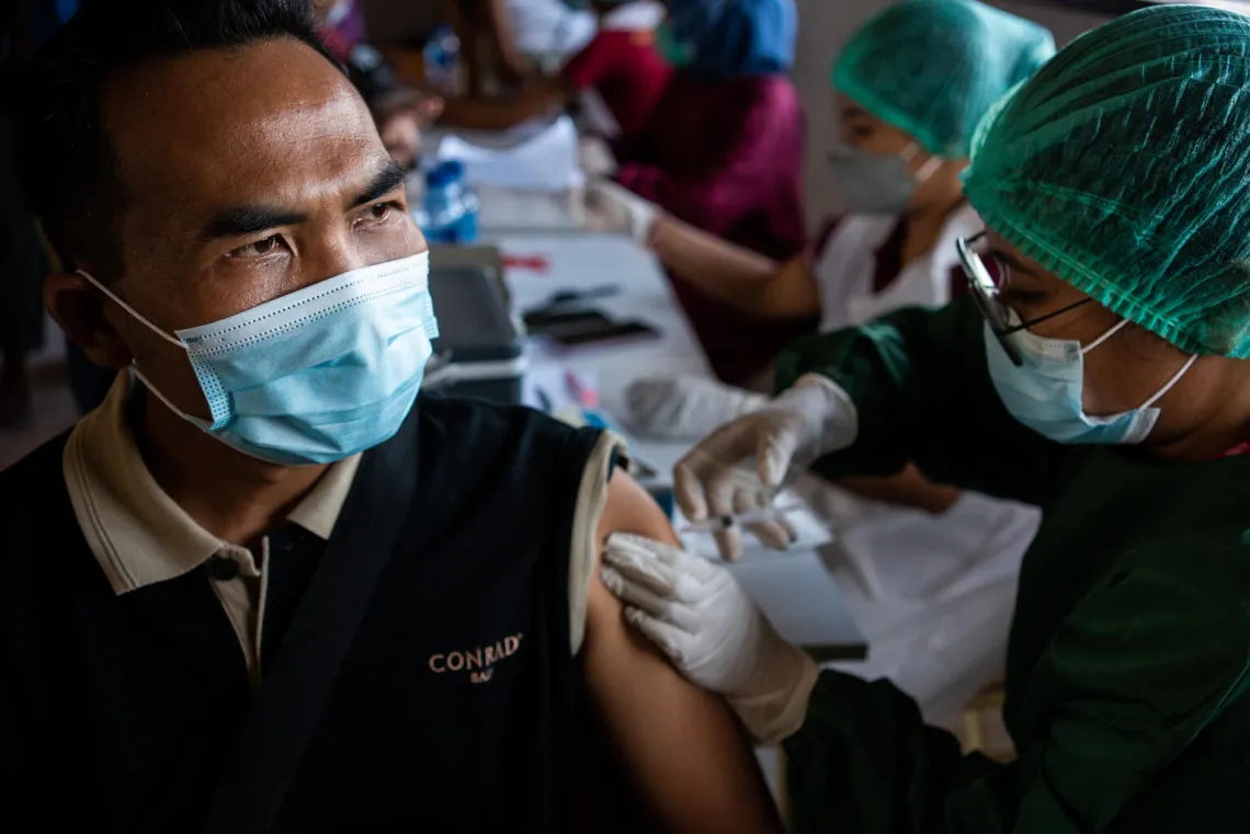 A health worker administers a dose of the COVAX COVID-19 vaccine