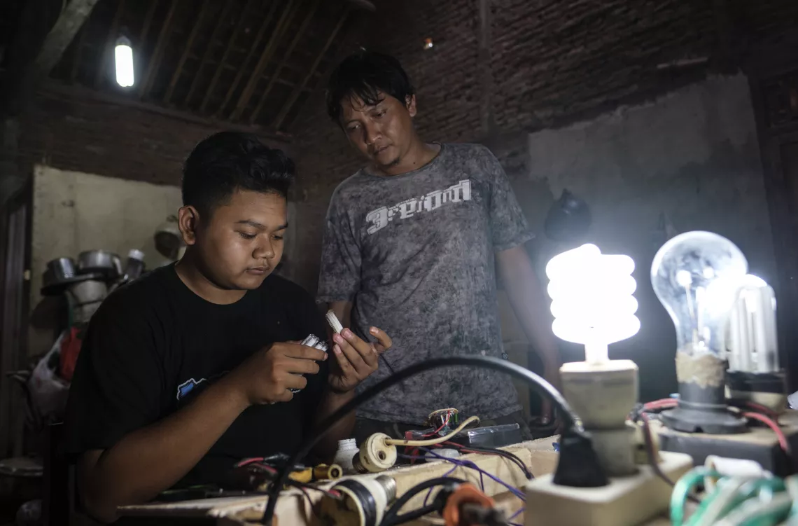 Bagus learns how to repair a lightbulb from his brother-in-law Ridwan.