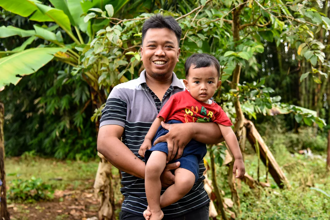 Imam Prambudi carries his son, Dwipayudha Prambudhi, age 2, at his home backyard in Bobotsari, Purbalingga.