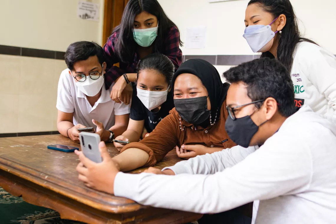 A group of teenage boys and girls are discussing and downloading the Oky app.