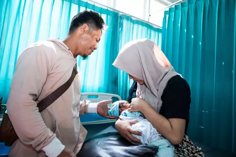 A mother breastfeeding her child while accompanied by her husband, on a hospital bed in RSUD Sakra, East Lombok, East Nusa Tenggara. 