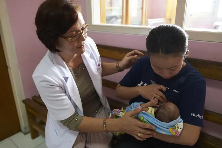 A doctor shows a mother how to hold a baby during breastfeeding 