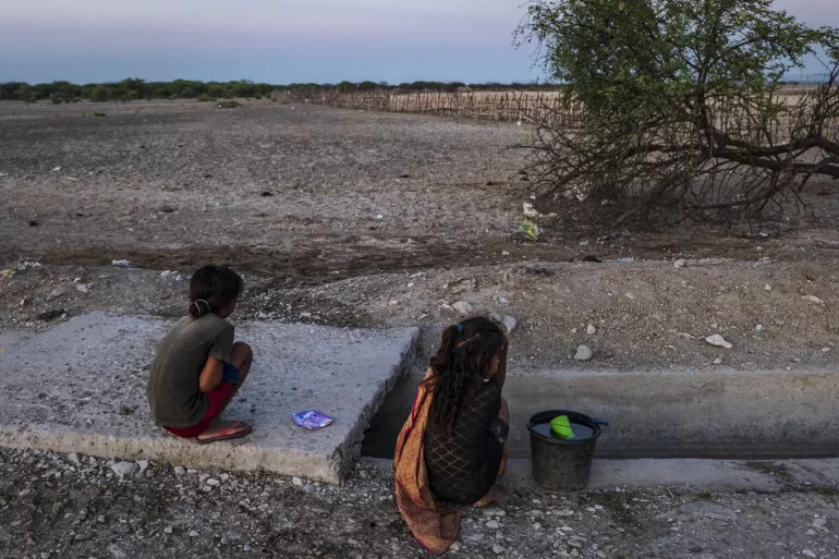 Children collect water from an irrigation canal during the dry season
