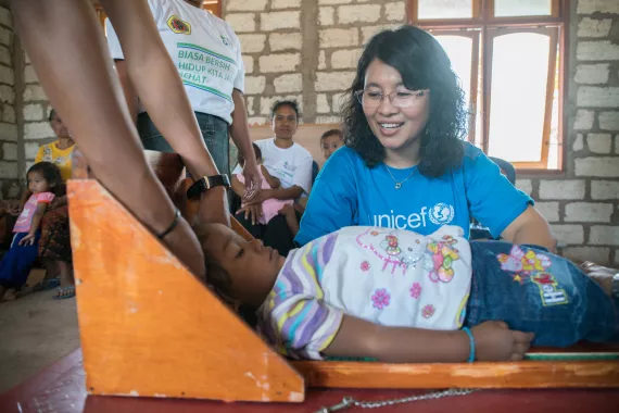 A UNICEF Nutrition Officer speaks with a child who is being checked as part of monthly nutrition screening at a village Health Post in Kupang District, Nusa Tenggara Timur Province, Indonesia. 
