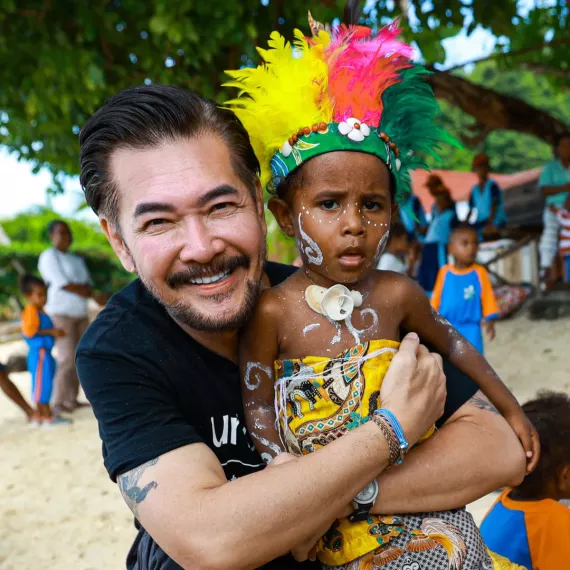 Ferry Salim poses with a child in Papuan traditional attire