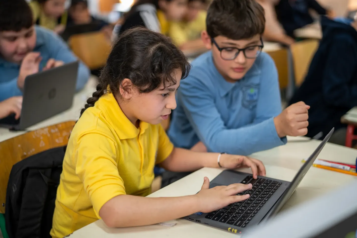 Two young students look at a laptop screen