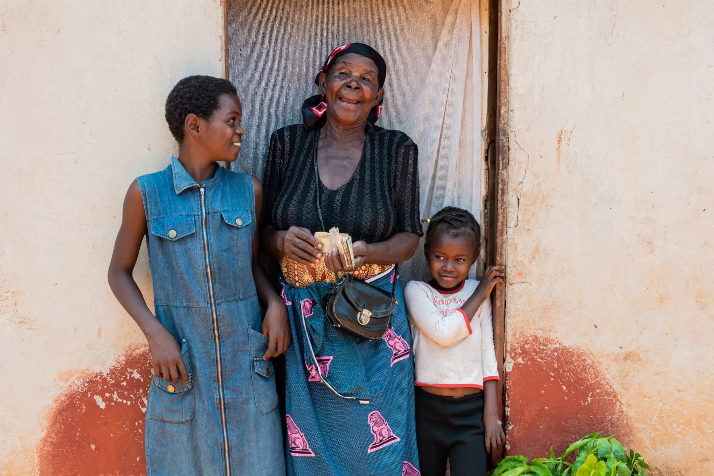 An older woman holding cash and flanked by two children