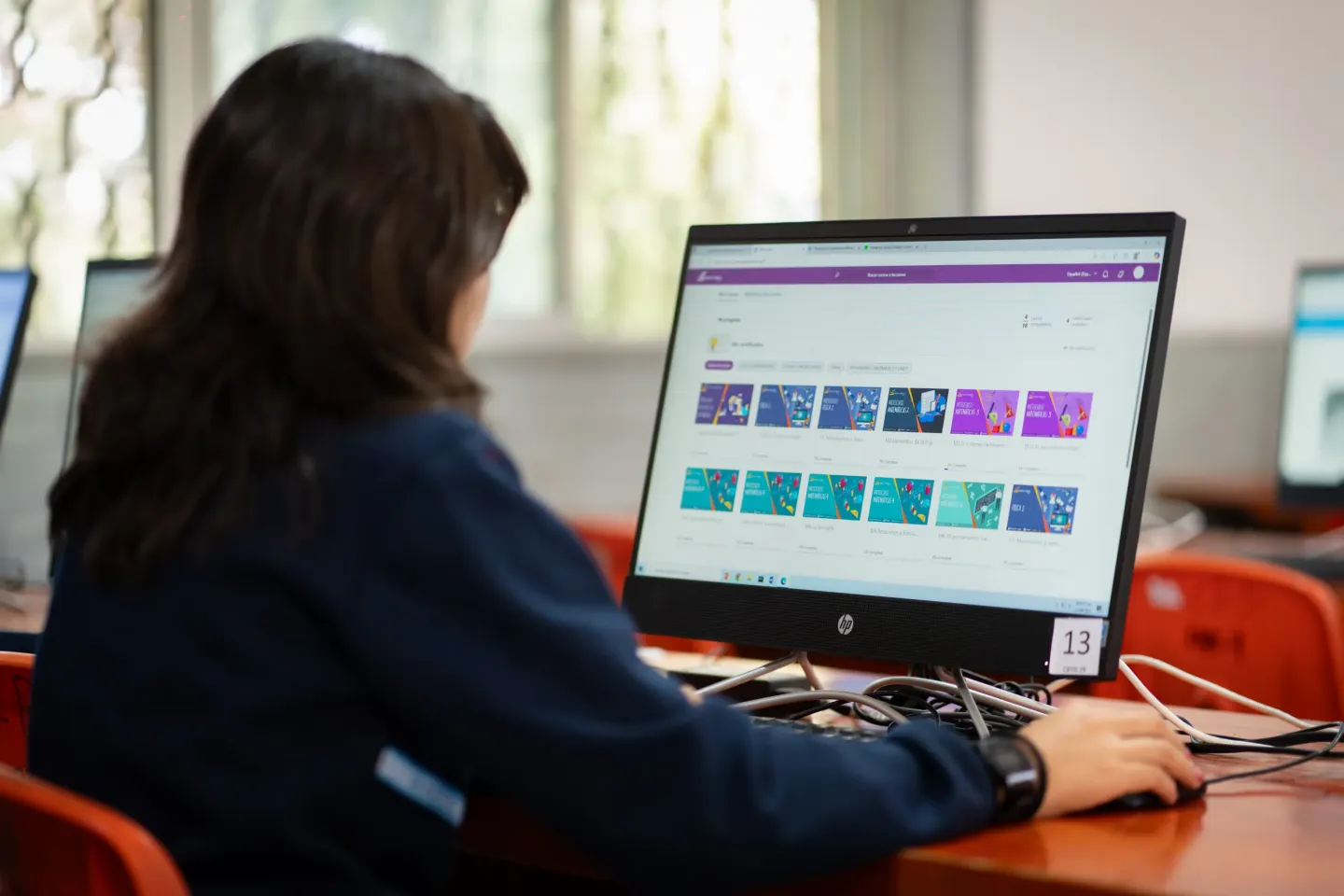 A girl is seen from behind working on her laptop