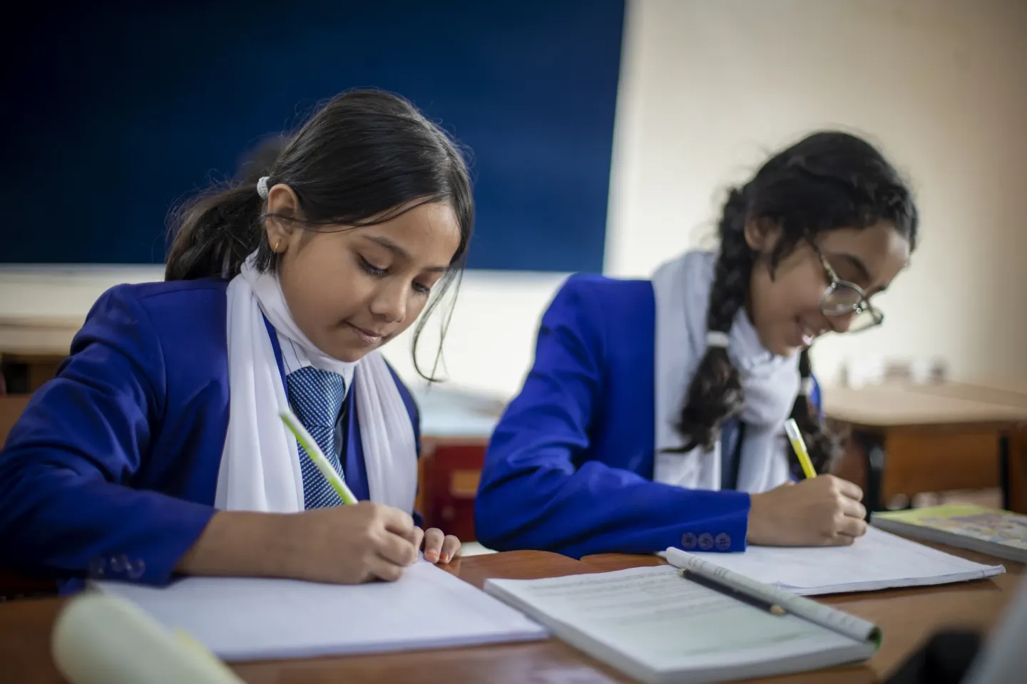 Two students at school, writing in their notebooks.