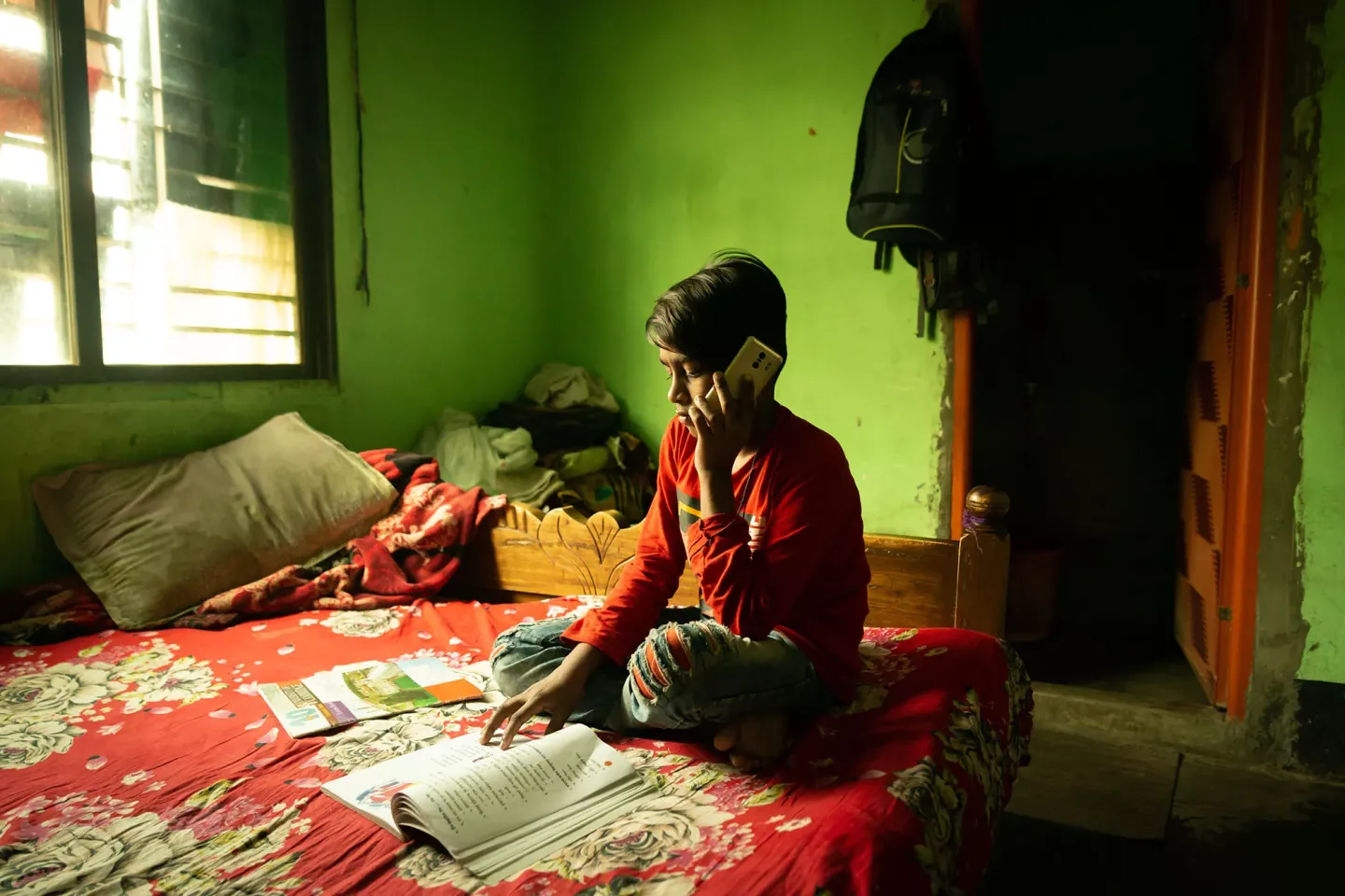 A boy (12) using a mobile phone during his daily education lesson through remote learning method
