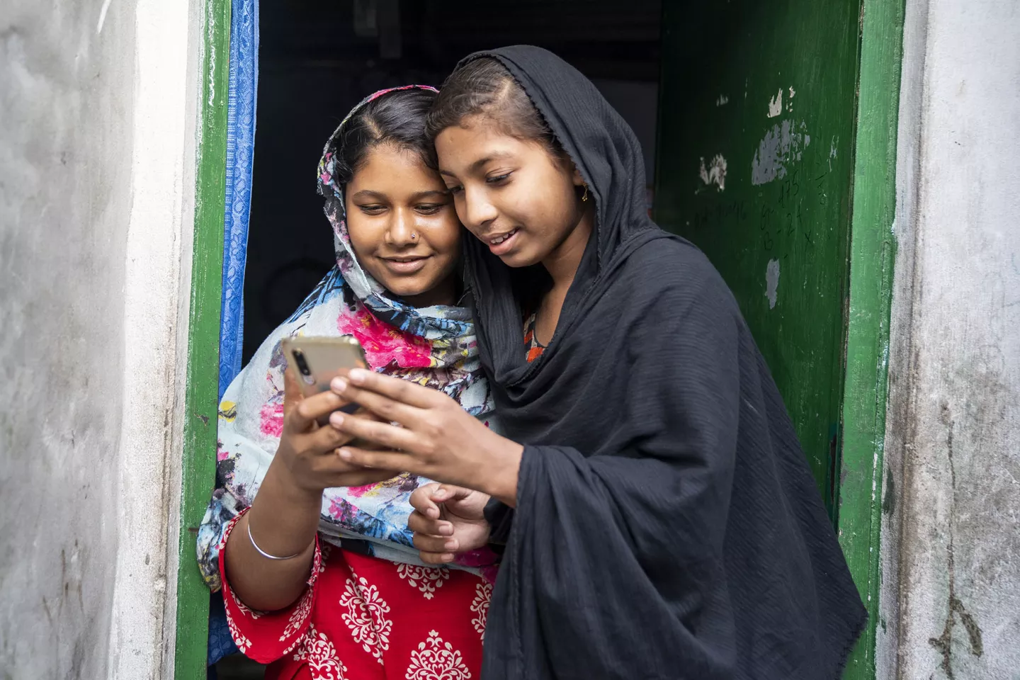 A girl, 14, is showing her friend something in her mobile phone