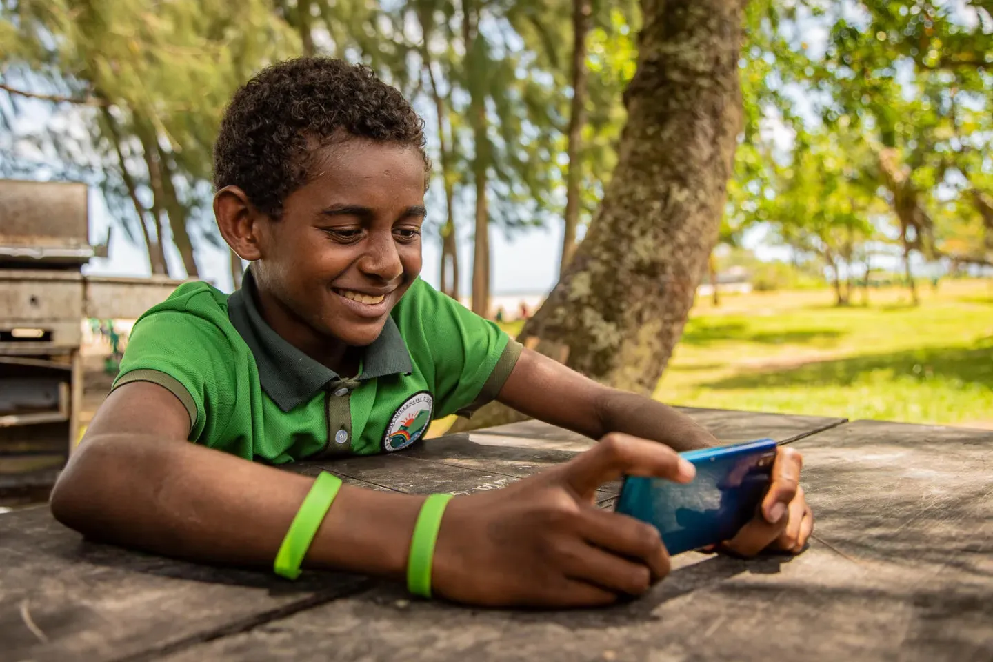 A young boy smiling and playing a game on his mobile device