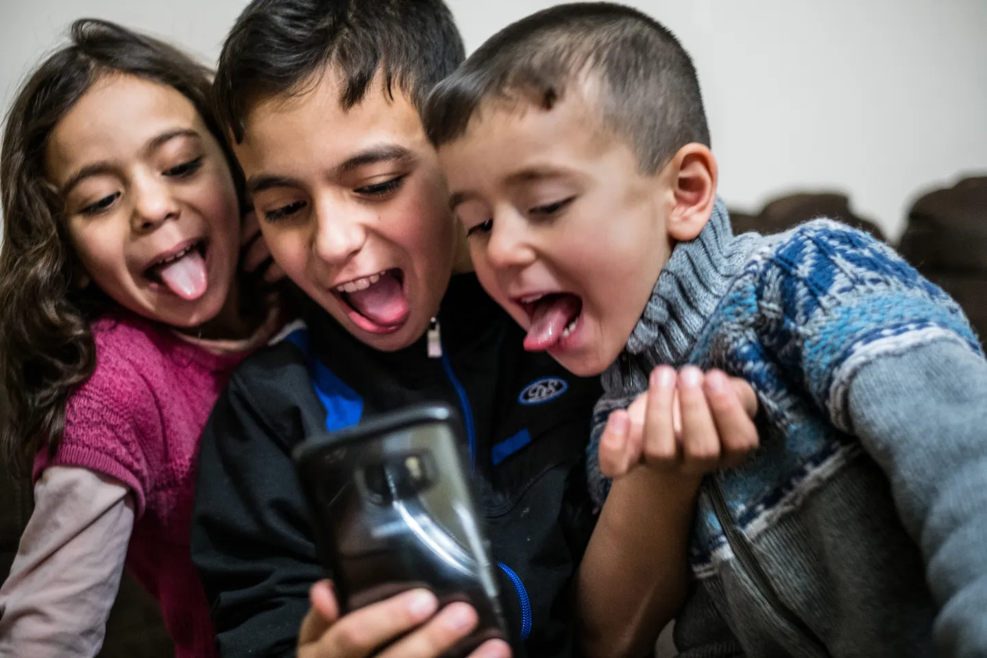 Kids make silly faces while looking into a smart phone