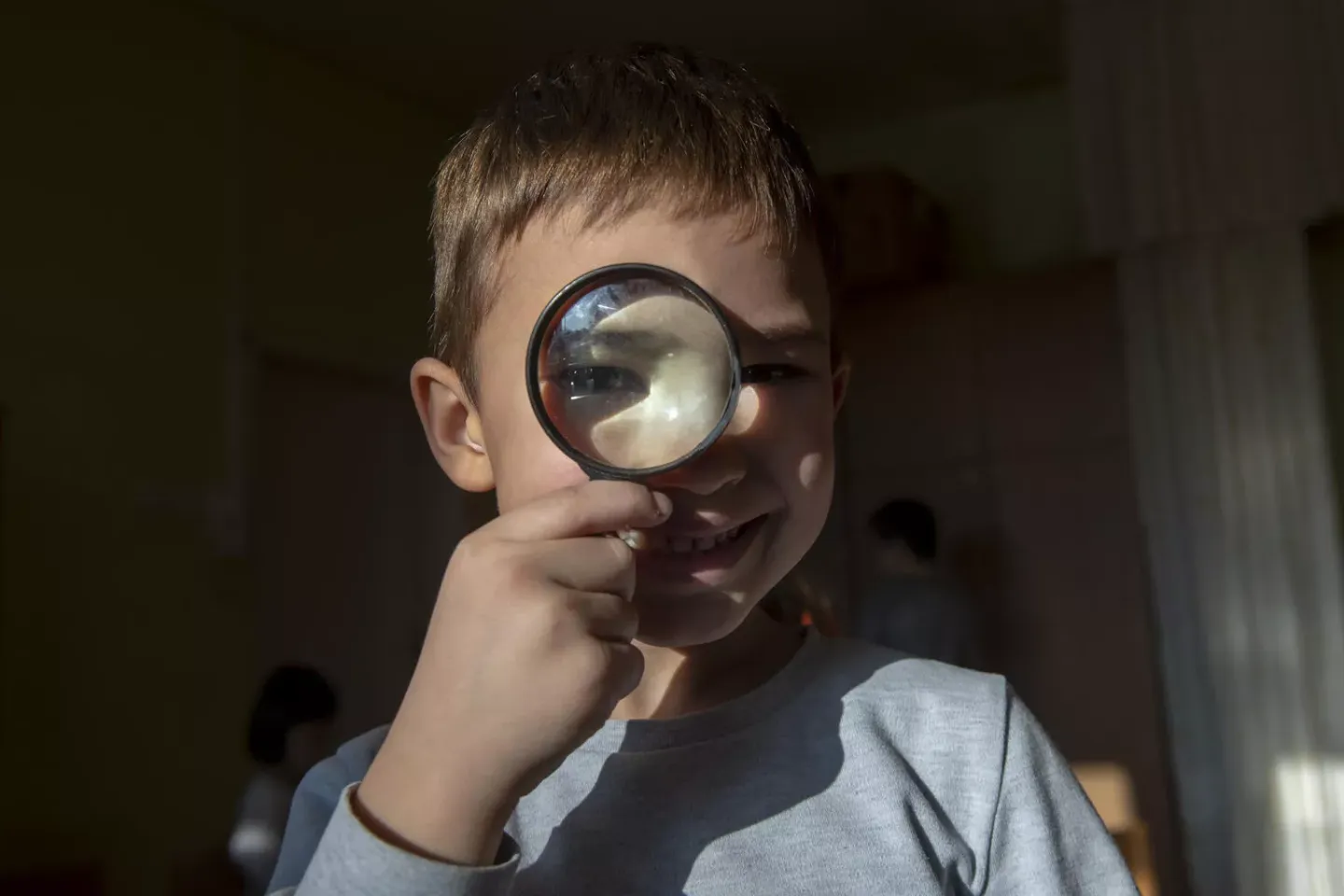 A young boy looks through a magnifying glass