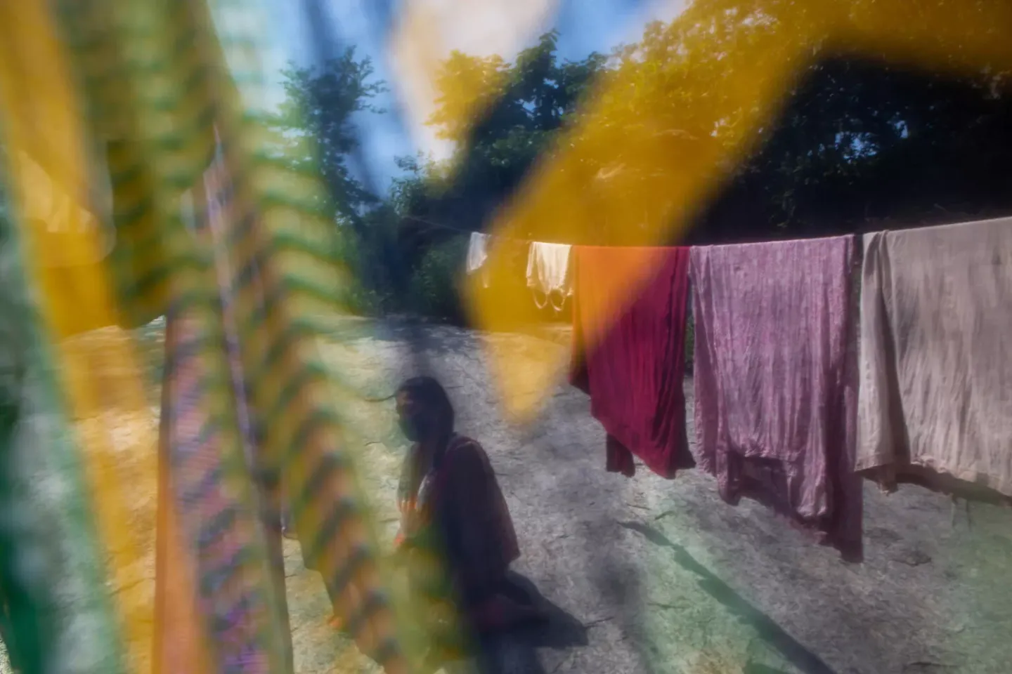 An adolescent girl seen among hanging laundry in soft focus