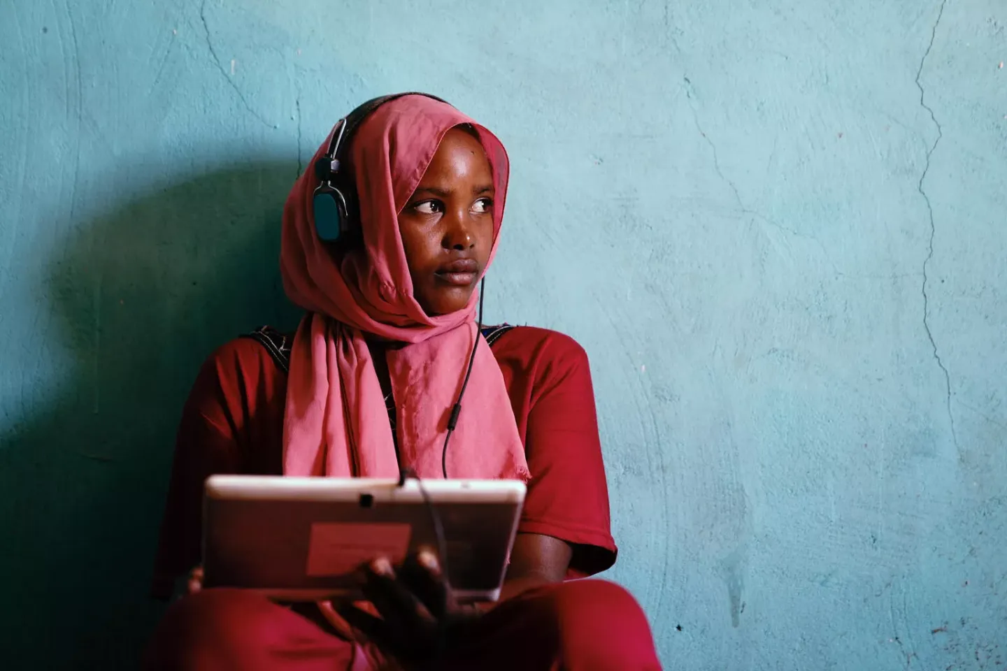 Girl wearing headphones and holding a tablet