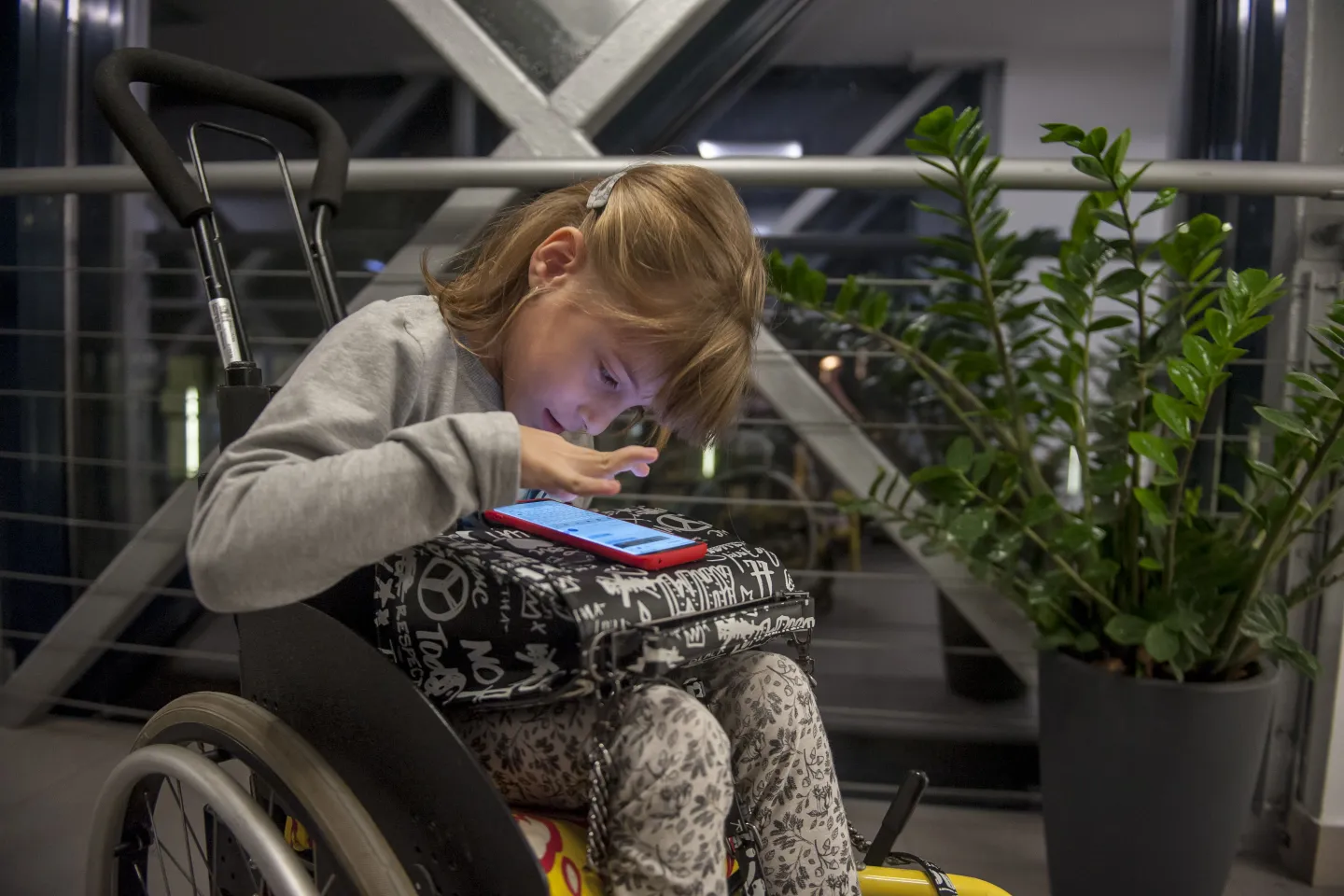 A girl in a wheel chair uses a smartphone