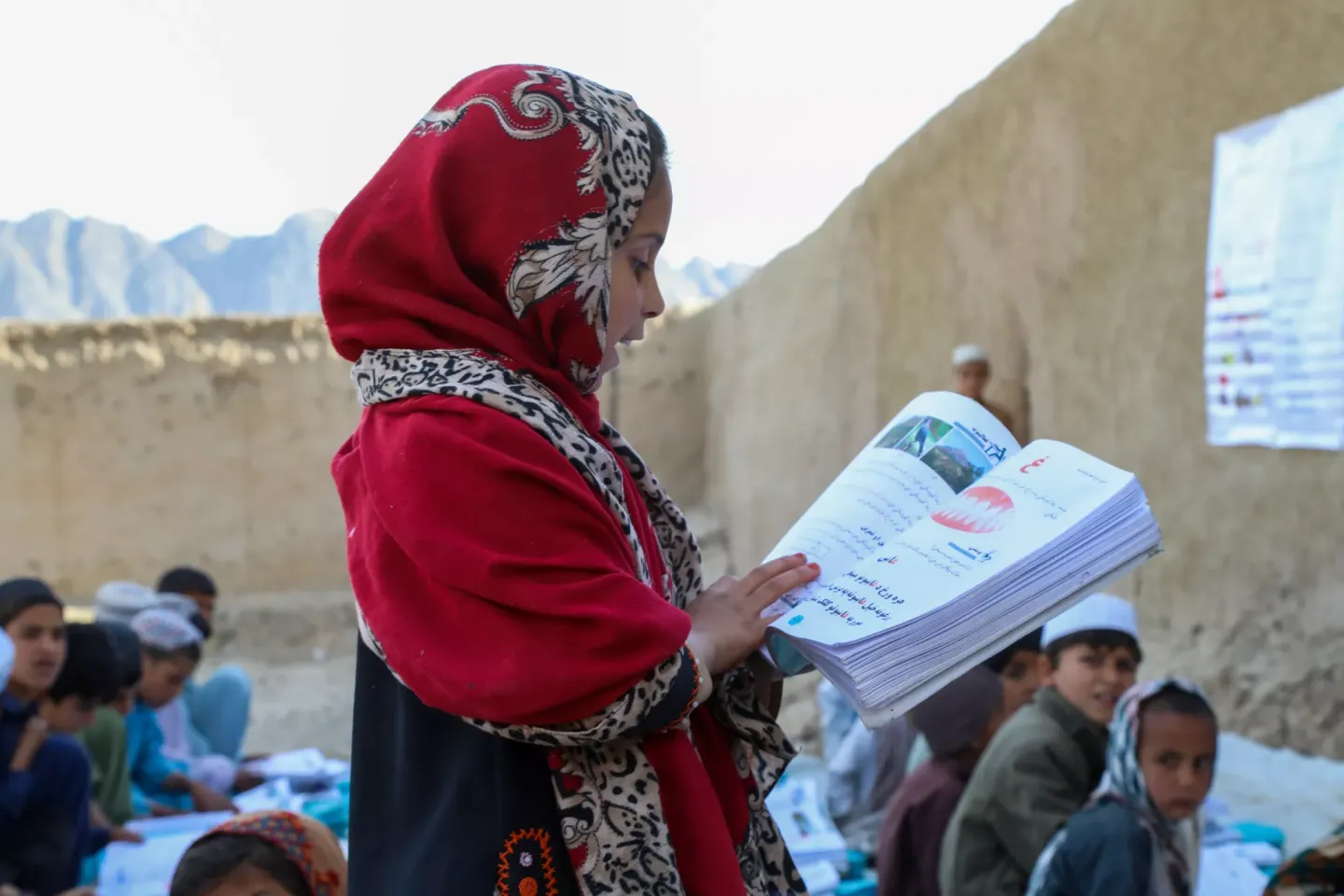 A girl reads a book in a class taking place outdoors