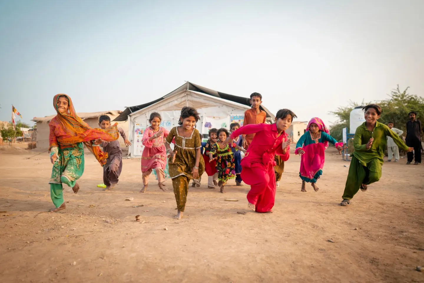 Children wearing colorful clothes run towards the camera 
