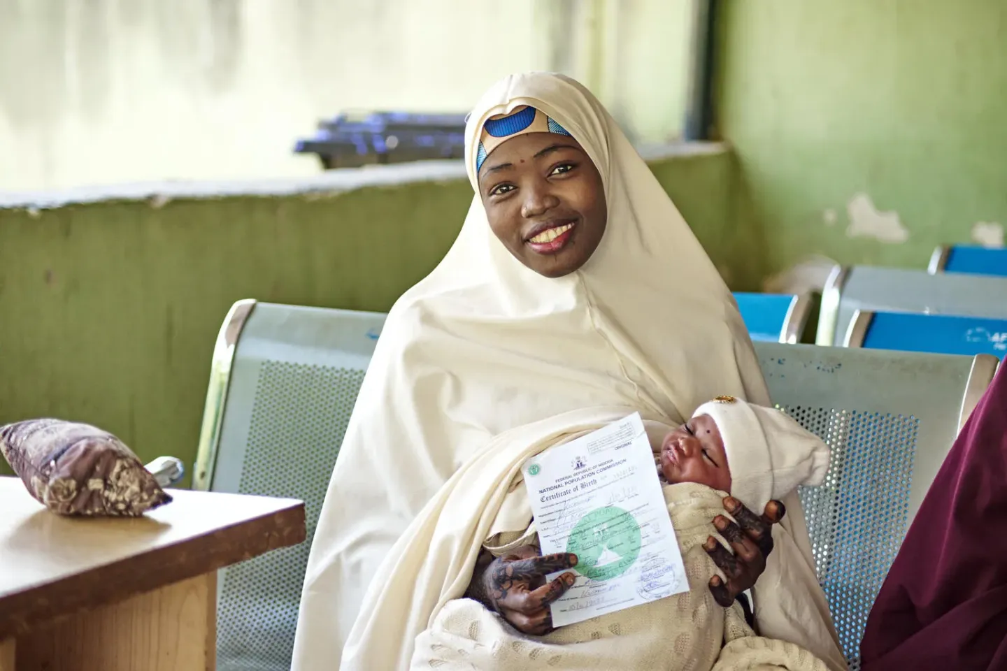 A mother poses with her infant and their new birth certificate