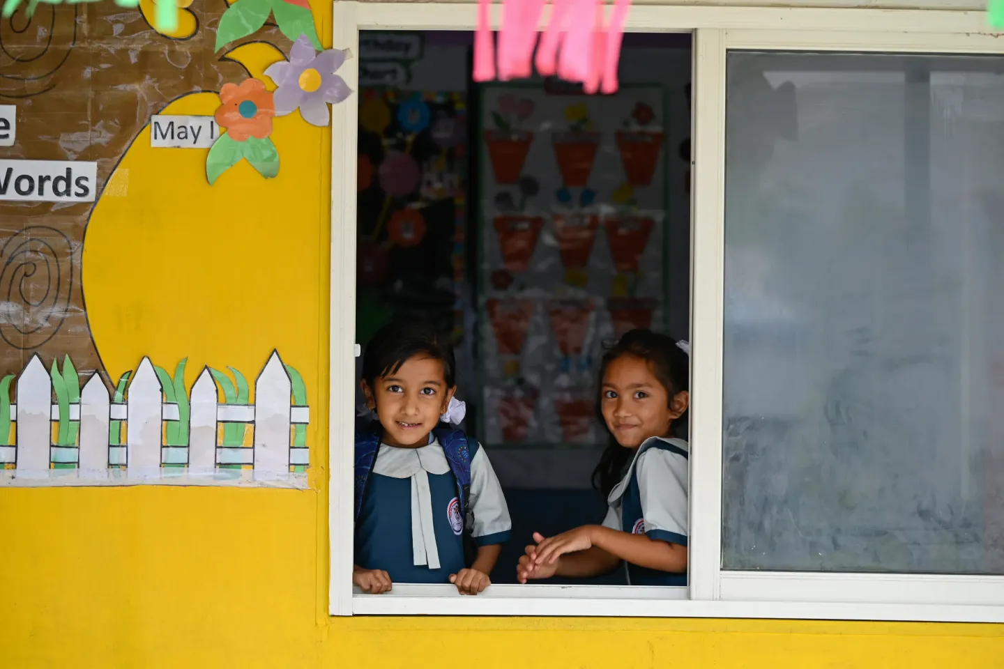 Two girls in a window frame smile for the camara.
