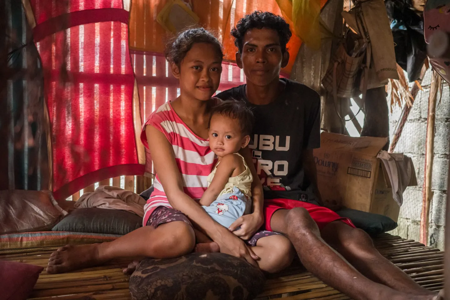 A young couple and their baby sitting in their home in the Philippines