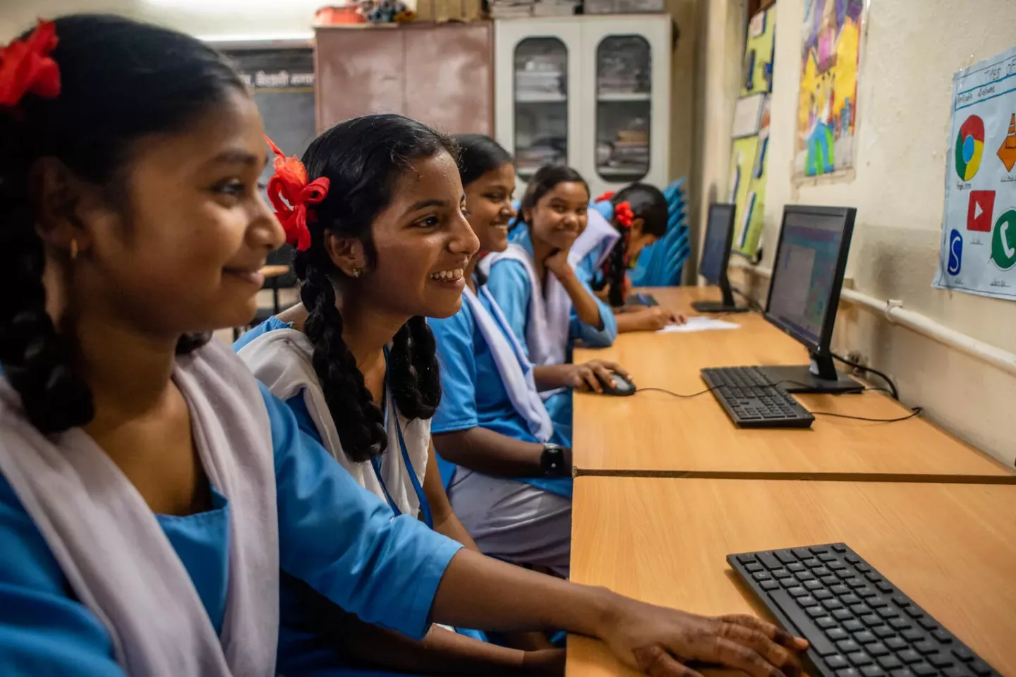 Children sitting at desks using computers and smiling