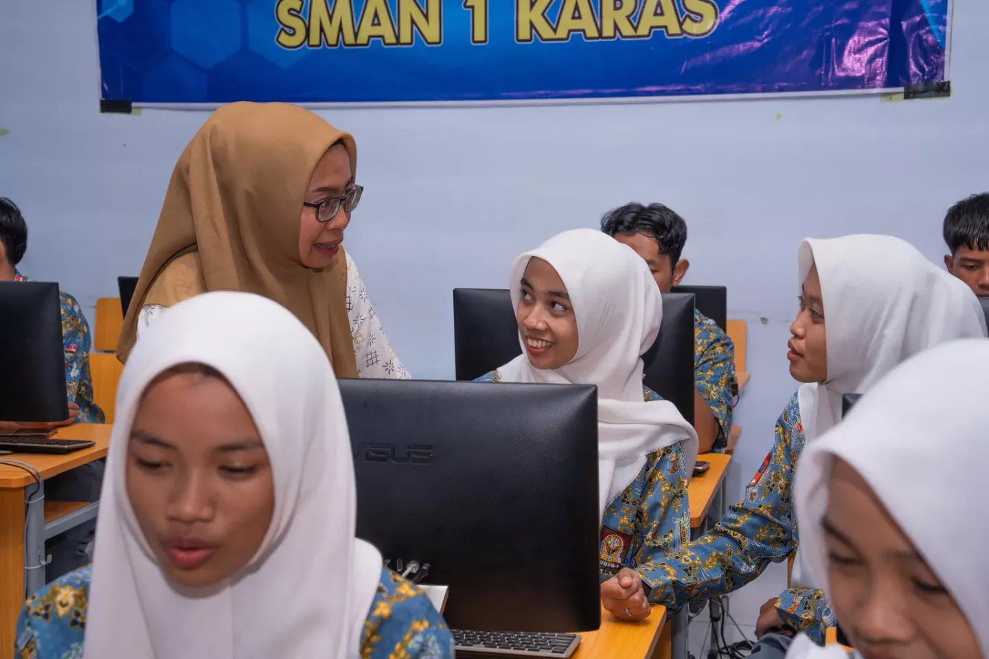 A teacher and her student using a computer in a classroom in Indonesia