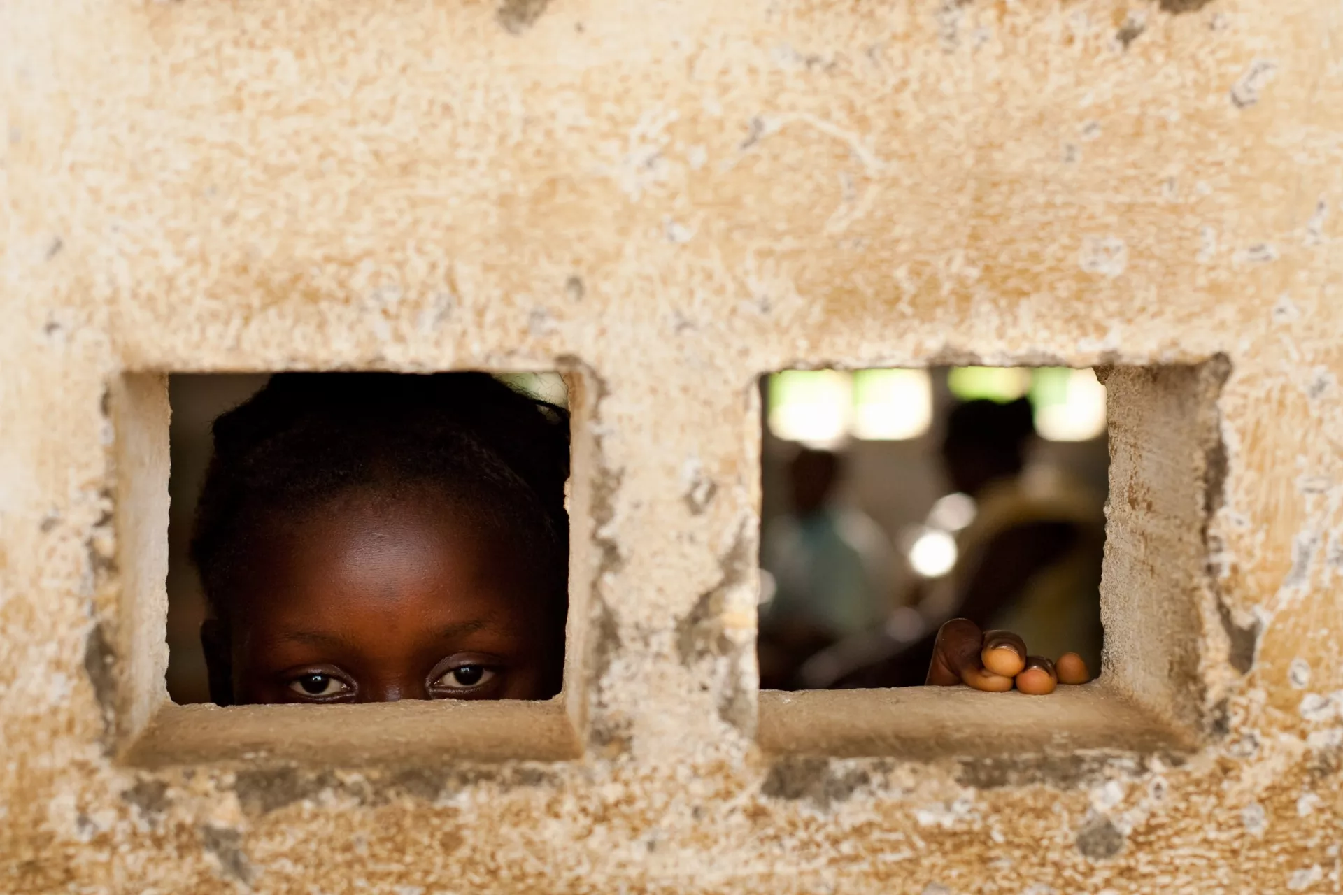 A person looks through a hole in a building wall