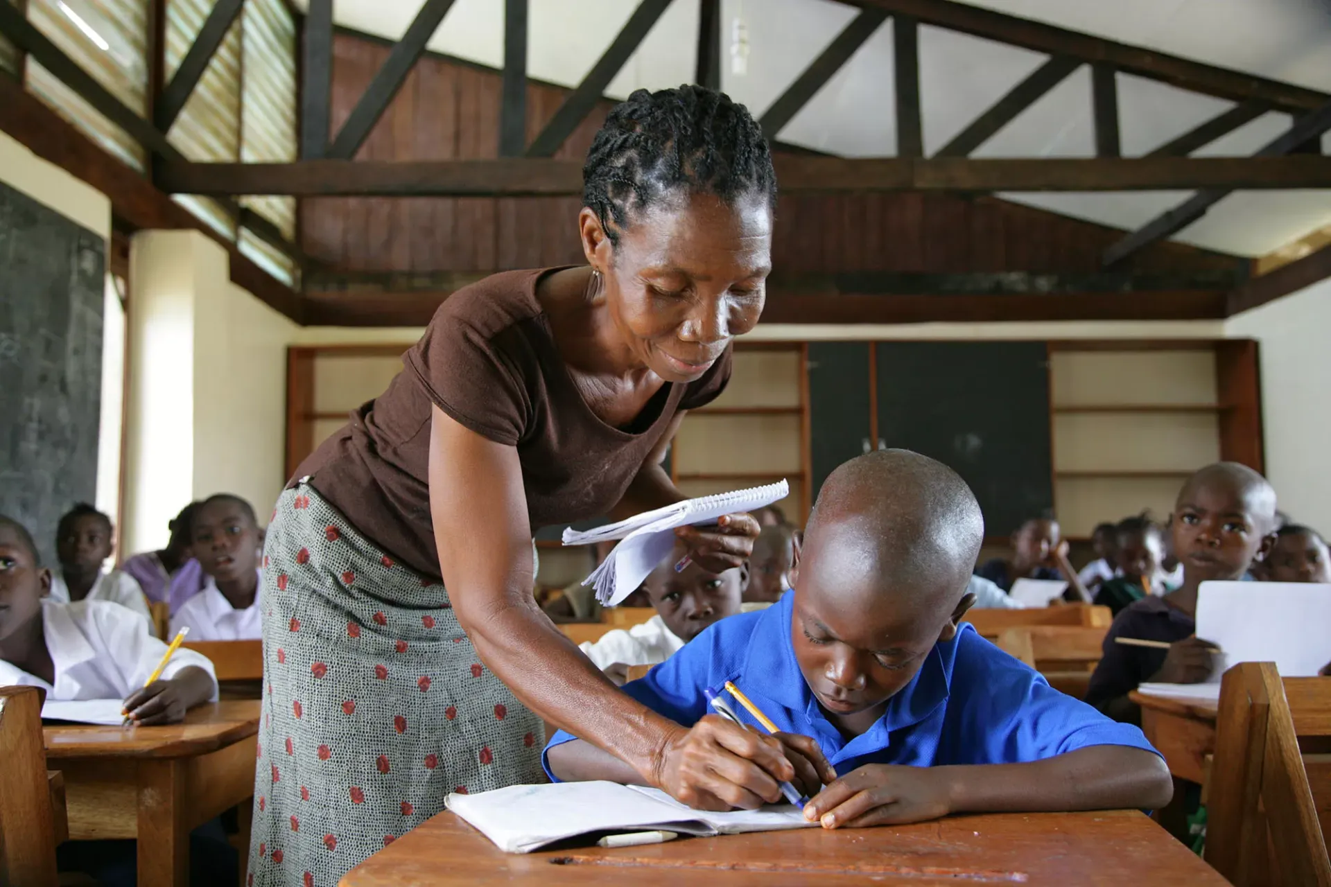 A teacher helps a student in a classroom, Liberia