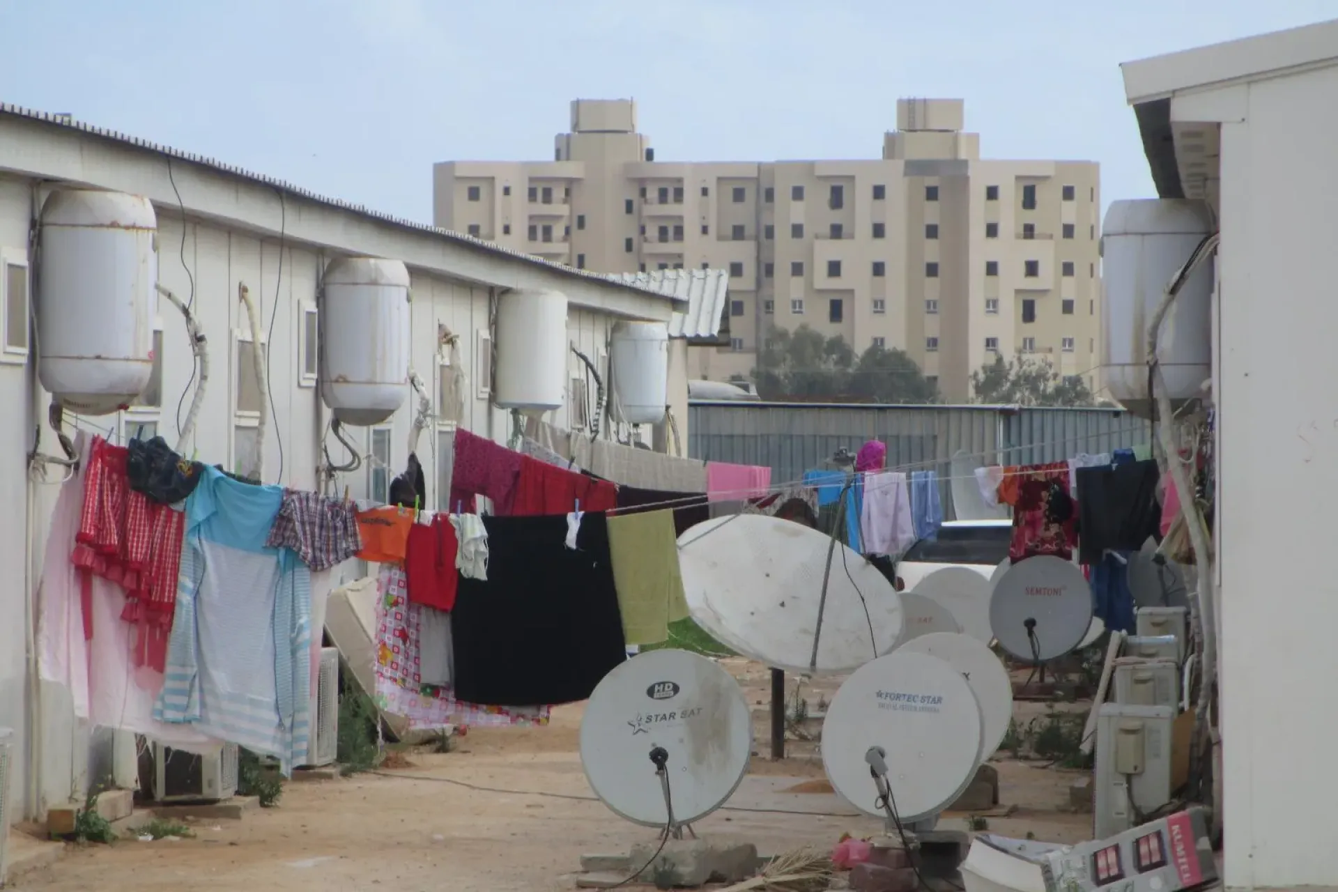 Laundry hangs to dry on clotheslines suspended among satellite dishes and air conditioning units between homes in a camp for internally displaced people