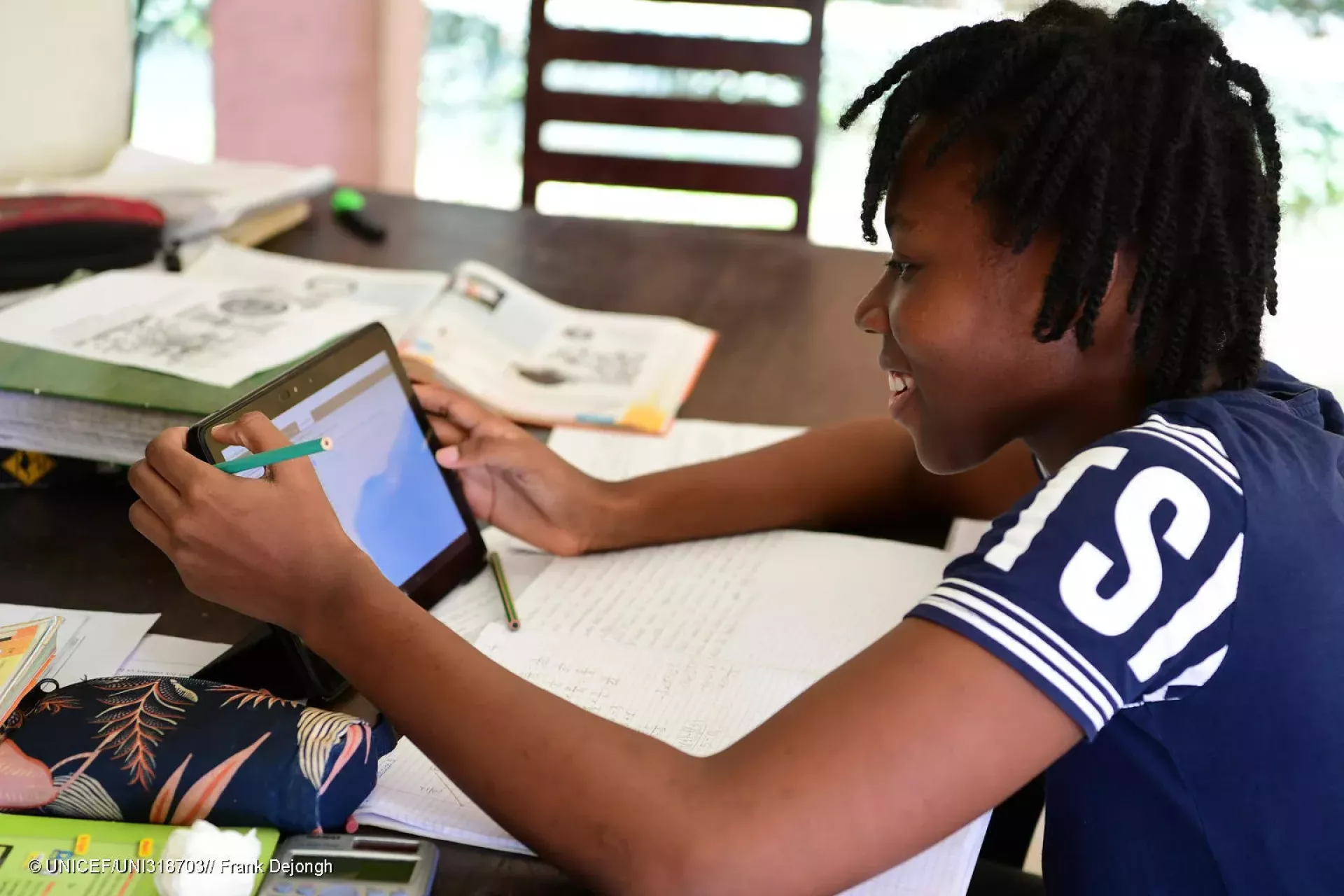A child smiling and working on a tablet