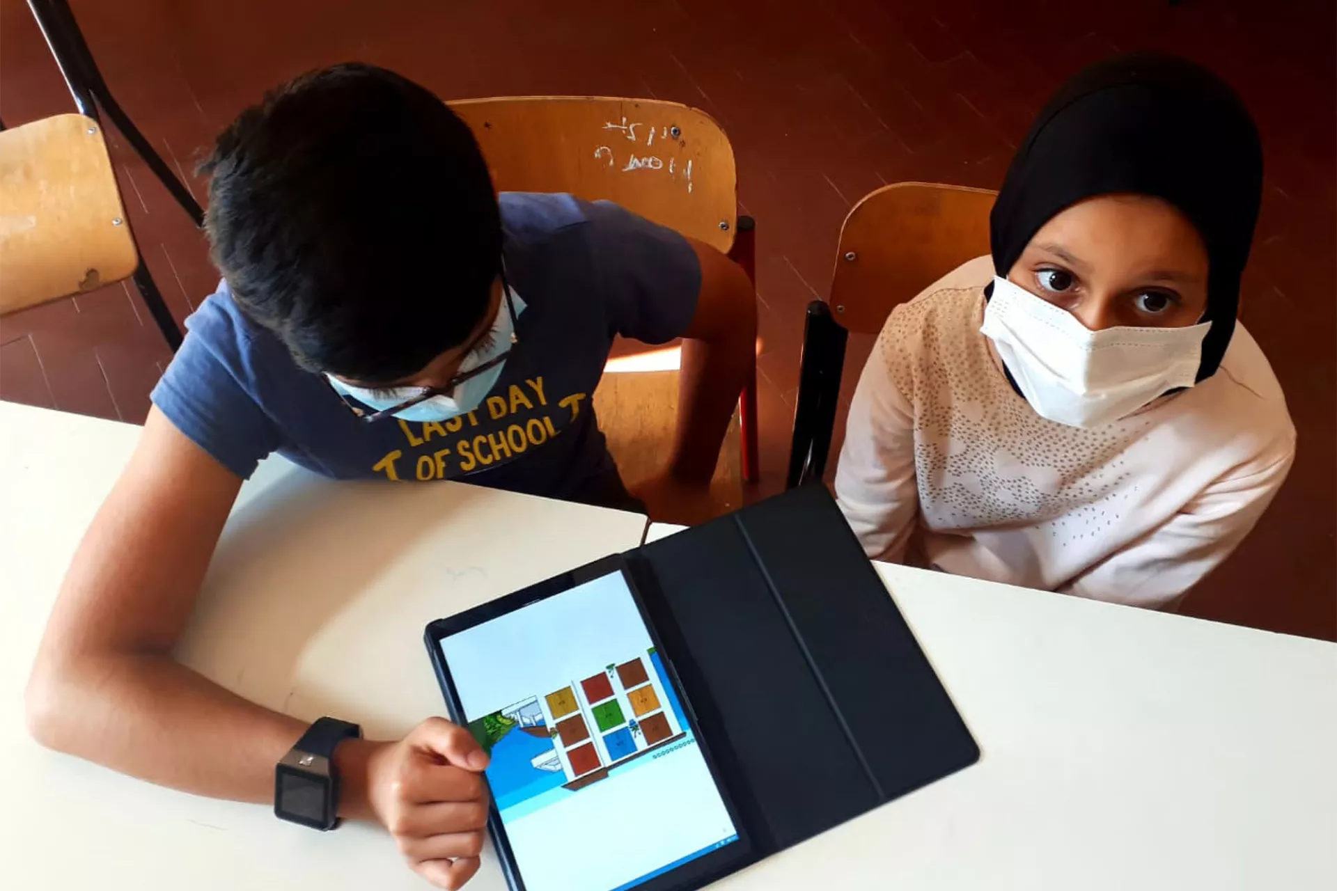 Two students, one working on a tablet