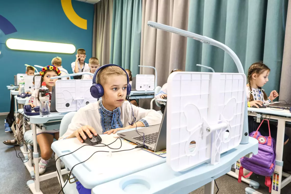A boy wearing headphones and studying with a computer