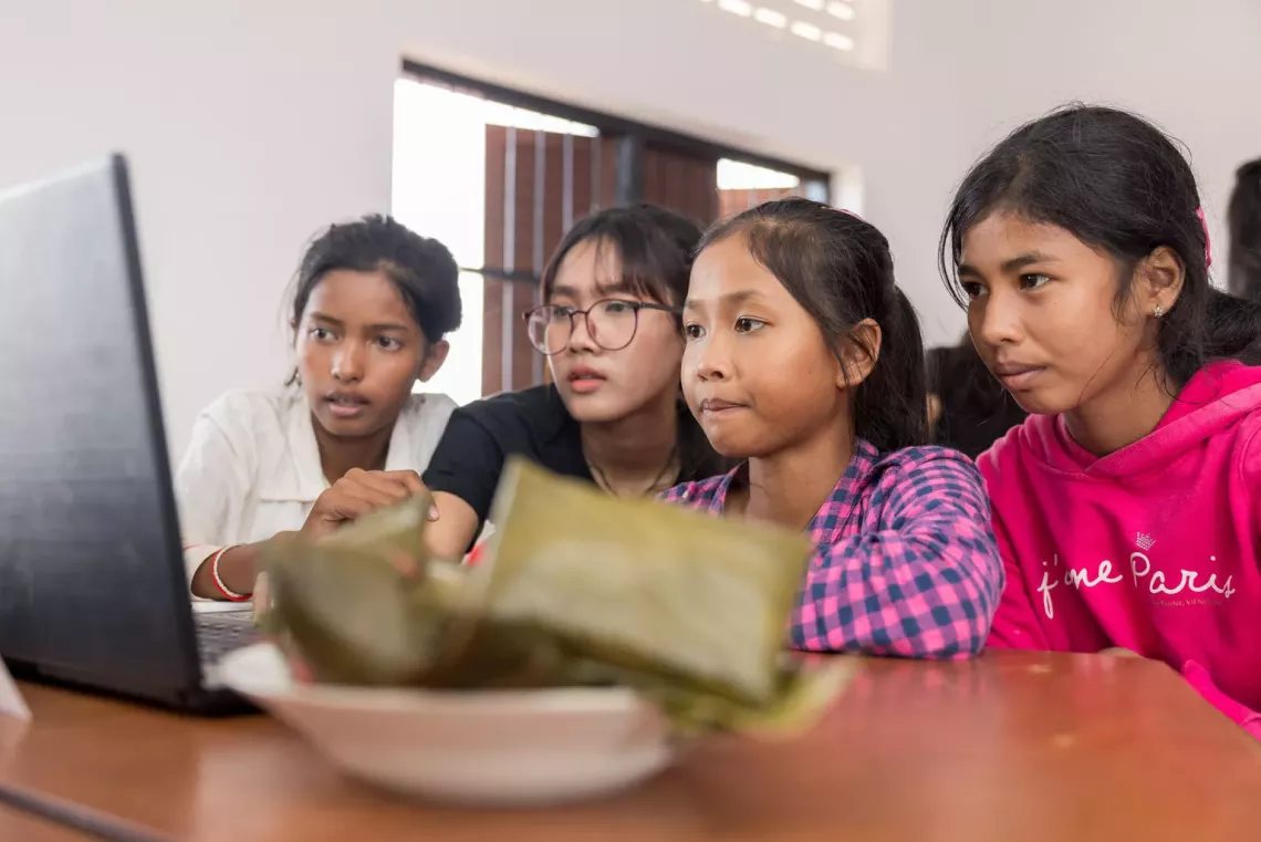 Four young girls playing with a single laptop 